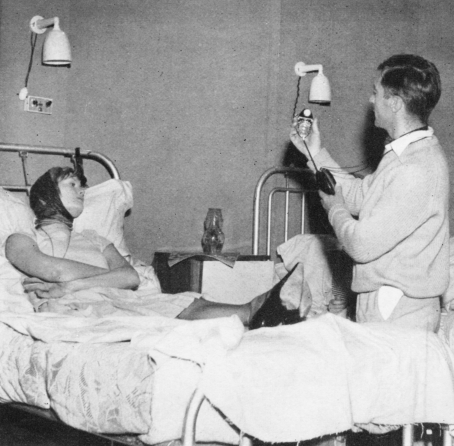 A man operates a lighting meter above a woman in a hospital bed